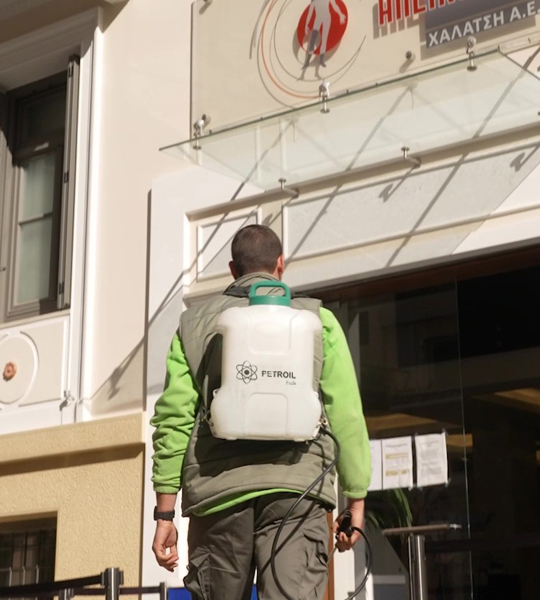 Απολυμαντής με στολή της Petroil Fuels βαδίζει προς το κτίριο της Απεικονιστικής Χαλάτση στον Πειραιά