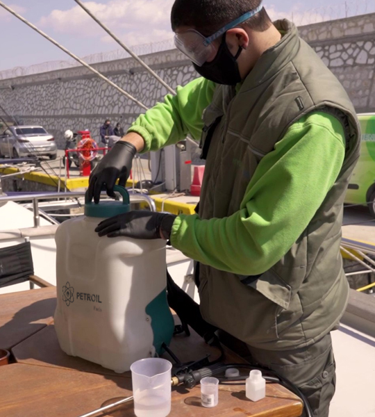Απολυμαντής με στολή της Petroil Fuels ετοιμάζει το απολυμαντικό προϊόν